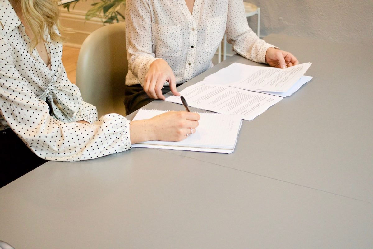 Woman Signing On White Printer Paper Beside Woman About To Touch The Documents 0acfe6272669184a9c67ce1cf3b9a8ae 2000 Scaled5 Tips for Streamlining Your Employment Verification Process