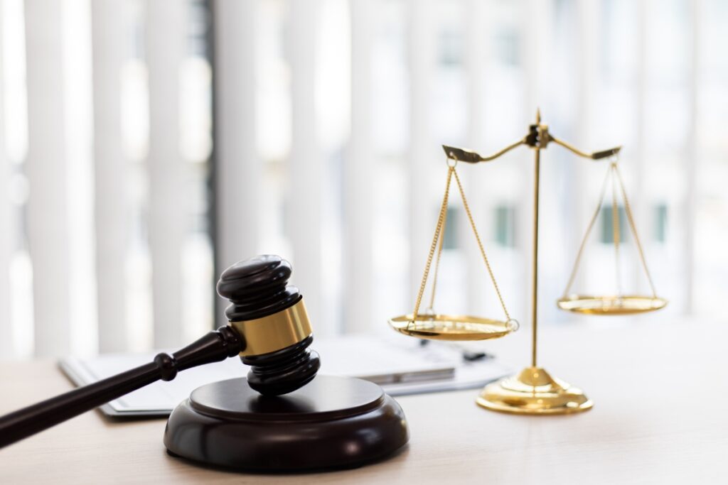 A judge's gavel and scales on a desk during court proceedings.