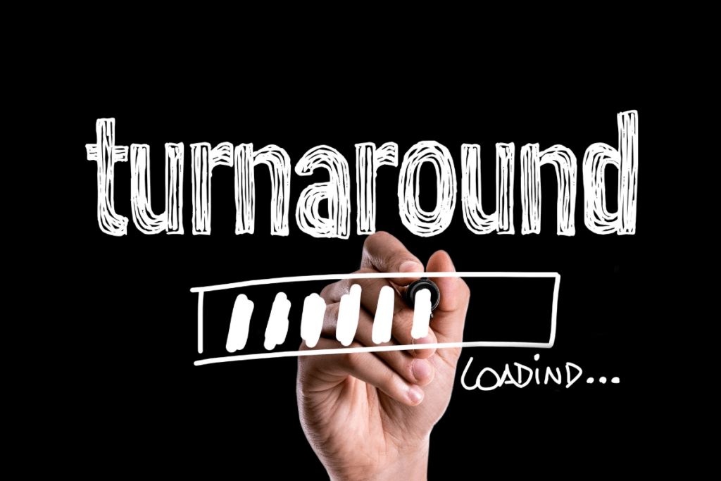 A person writing the word "turnaround" on a blackboard.