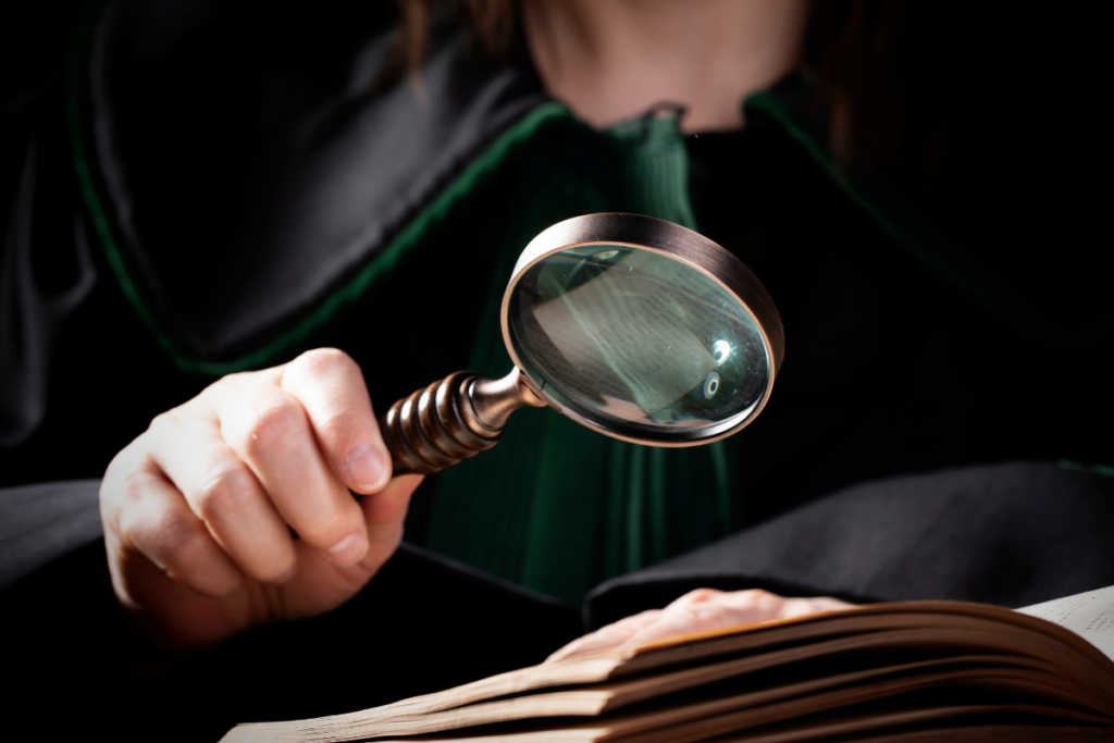 Legal Background Checks: Empowering Law Firms 2 A woman is conducting a legal background check, using a magnifying glass to carefully examine information in an open book.