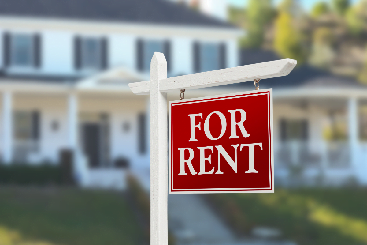 A house with a for rent sign in front.