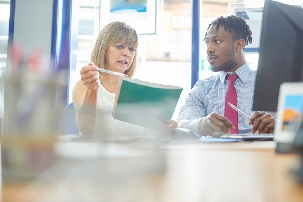 Two people discussing legal complaints at a desk in an office.