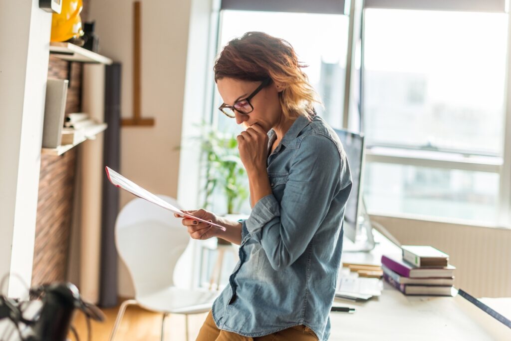 A woman examining legal complaints on a piece of paper in her office.