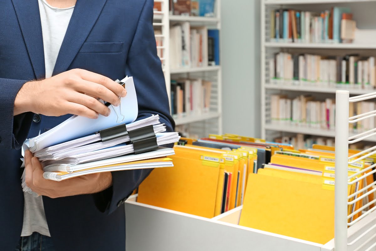 A man in a suit holding court records in a library.