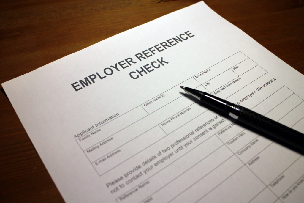 A pen is placed on top of a paper that says employer reference check.