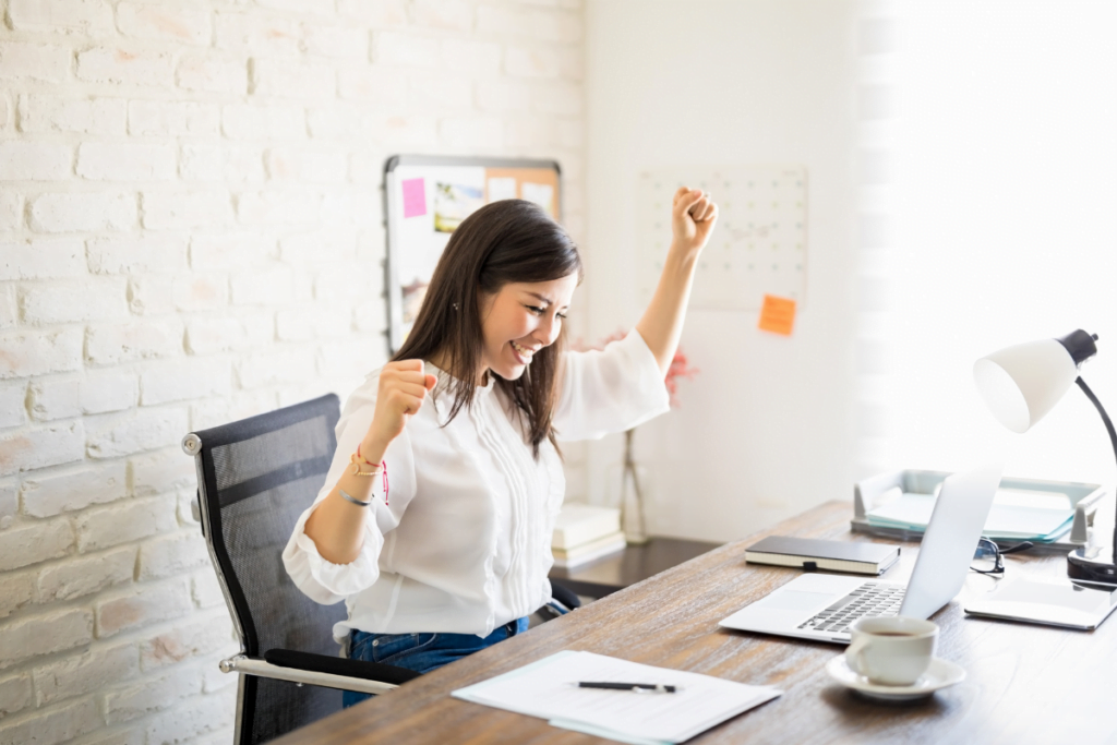 A woman celebrating success in the office after an effective employee screening.