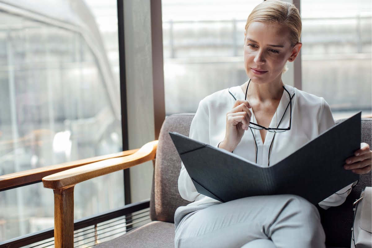 A business woman is sitting on a couch reading a folder, ensuring FCRA compliance.