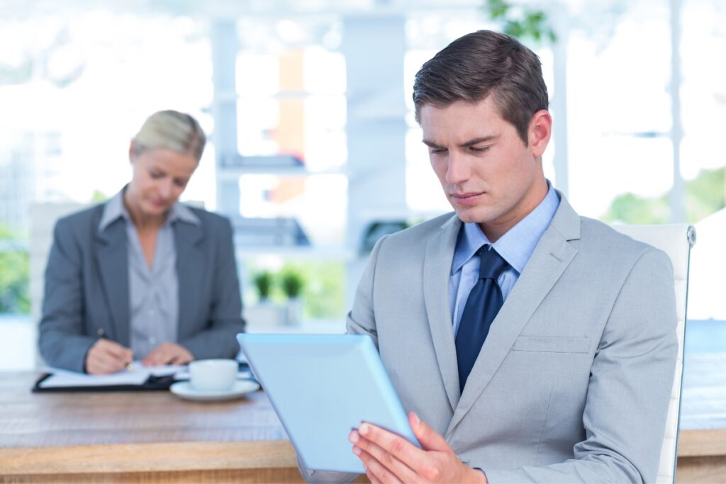 Two professionals ensuring FCRA compliance while using a tablet at their desk.