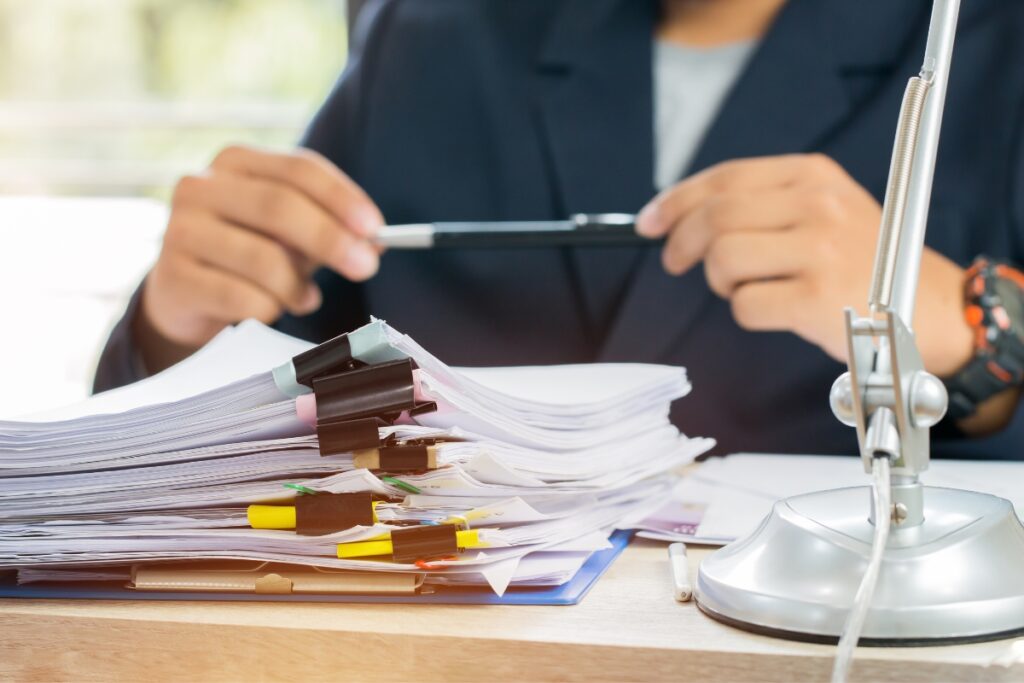 A man is sitting at a desk, meticulously reviewing a stack of papers for FCRA compliance.