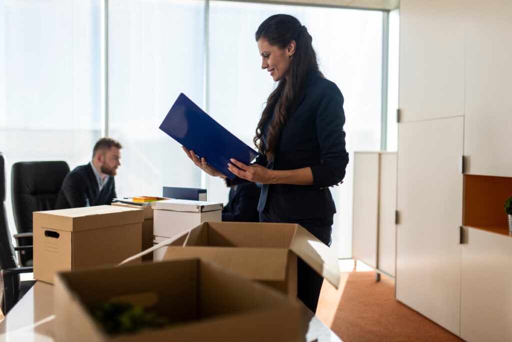 A woman in a business suit and a man in a suit standing next to a box, ensuring FCRA compliance.