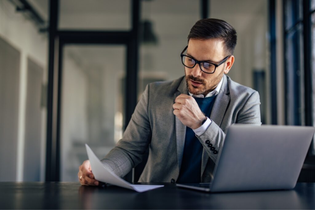 A businessman sitting at a desk with a laptop, ensuring FCRA compliance.